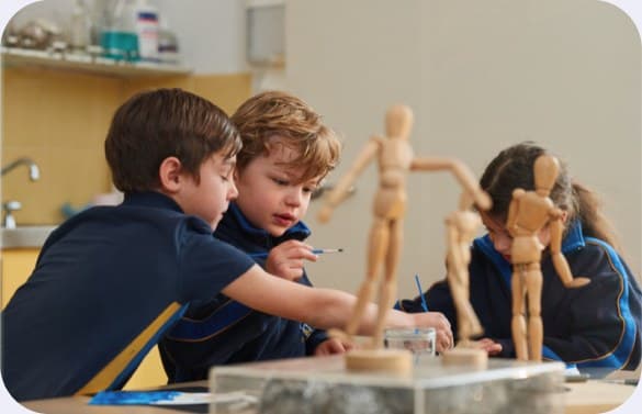 Two students painting while sketching from wooden artists' mannequins