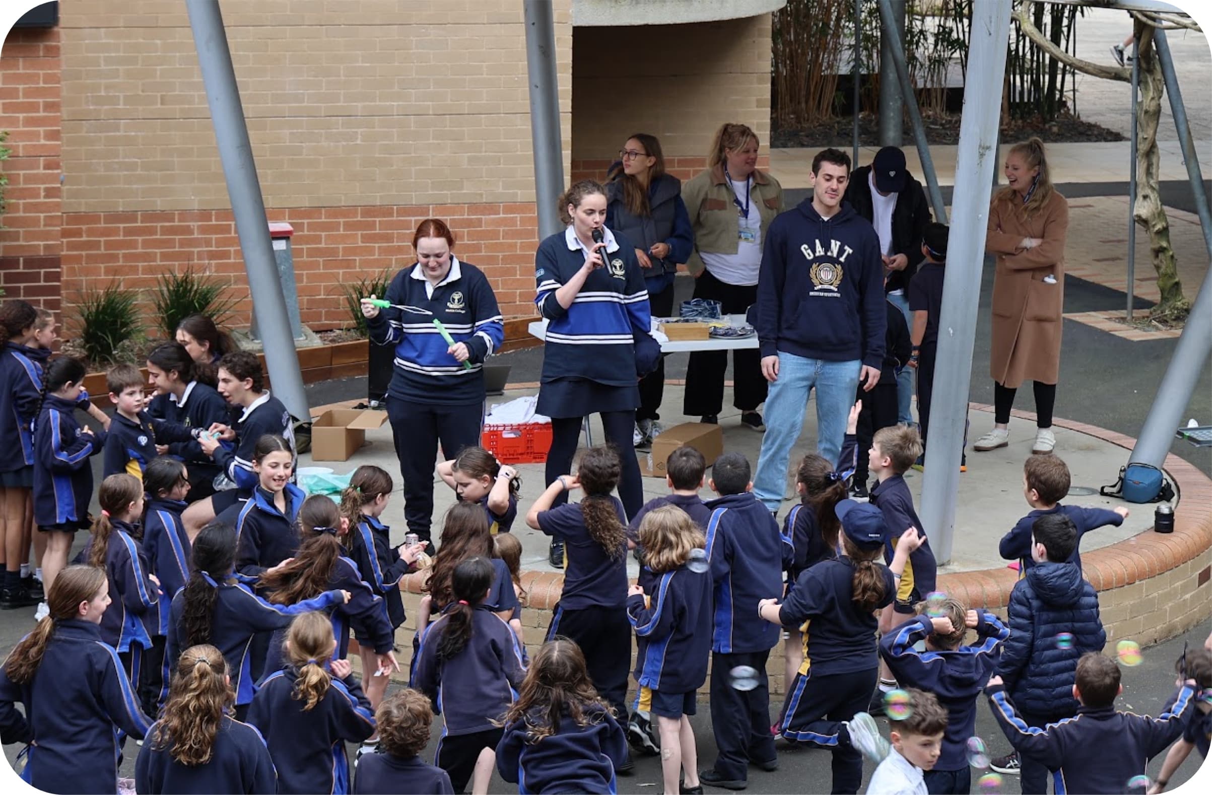 Students gathered under the courtyard canopy as bubbles drift over a Giving Day stall