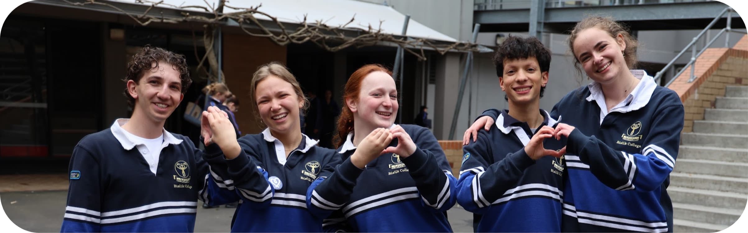 Senior students making heart shapes with their hands in the schoolyard
